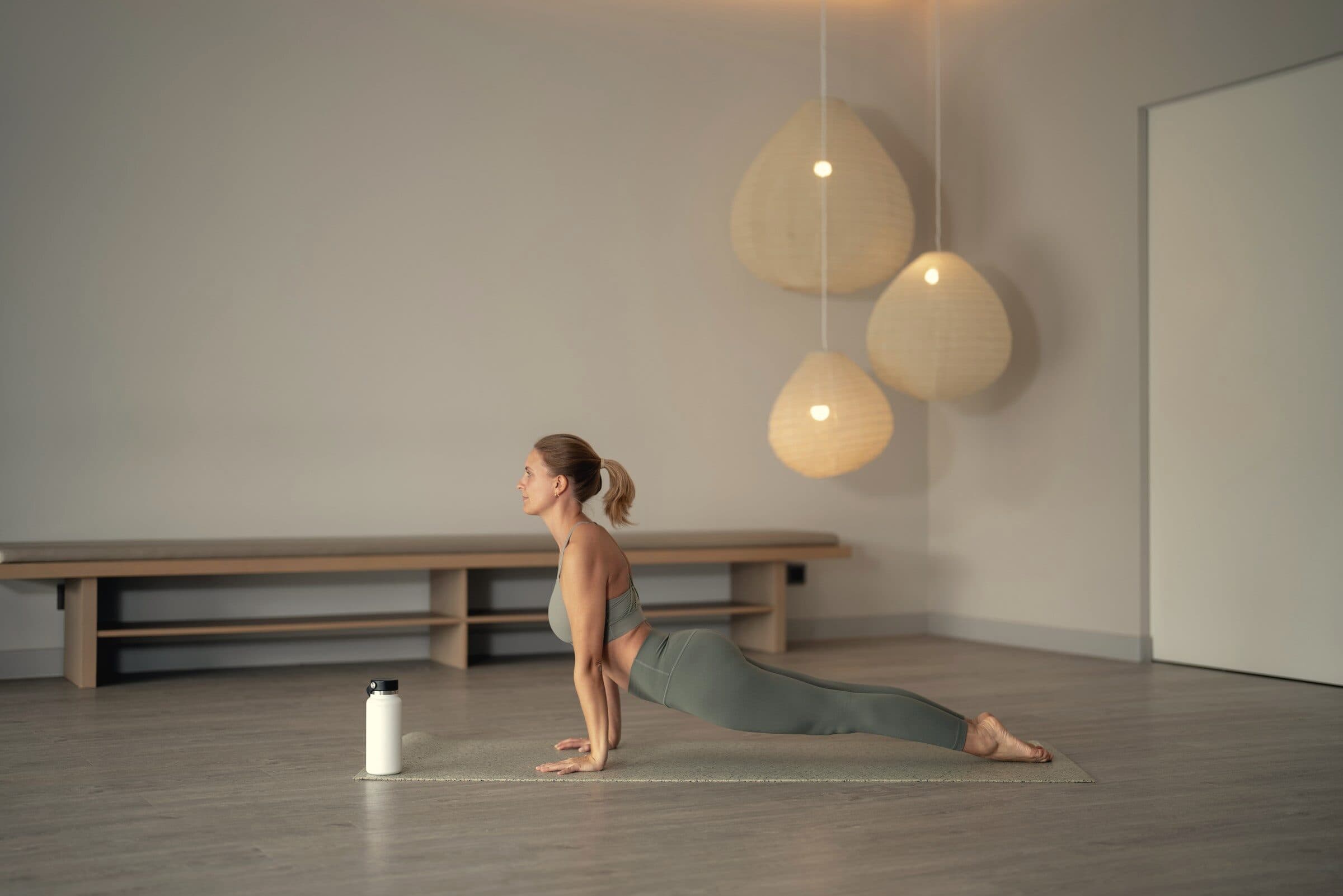 Kvinde i yogastilling i et roligt rum med papirlamper